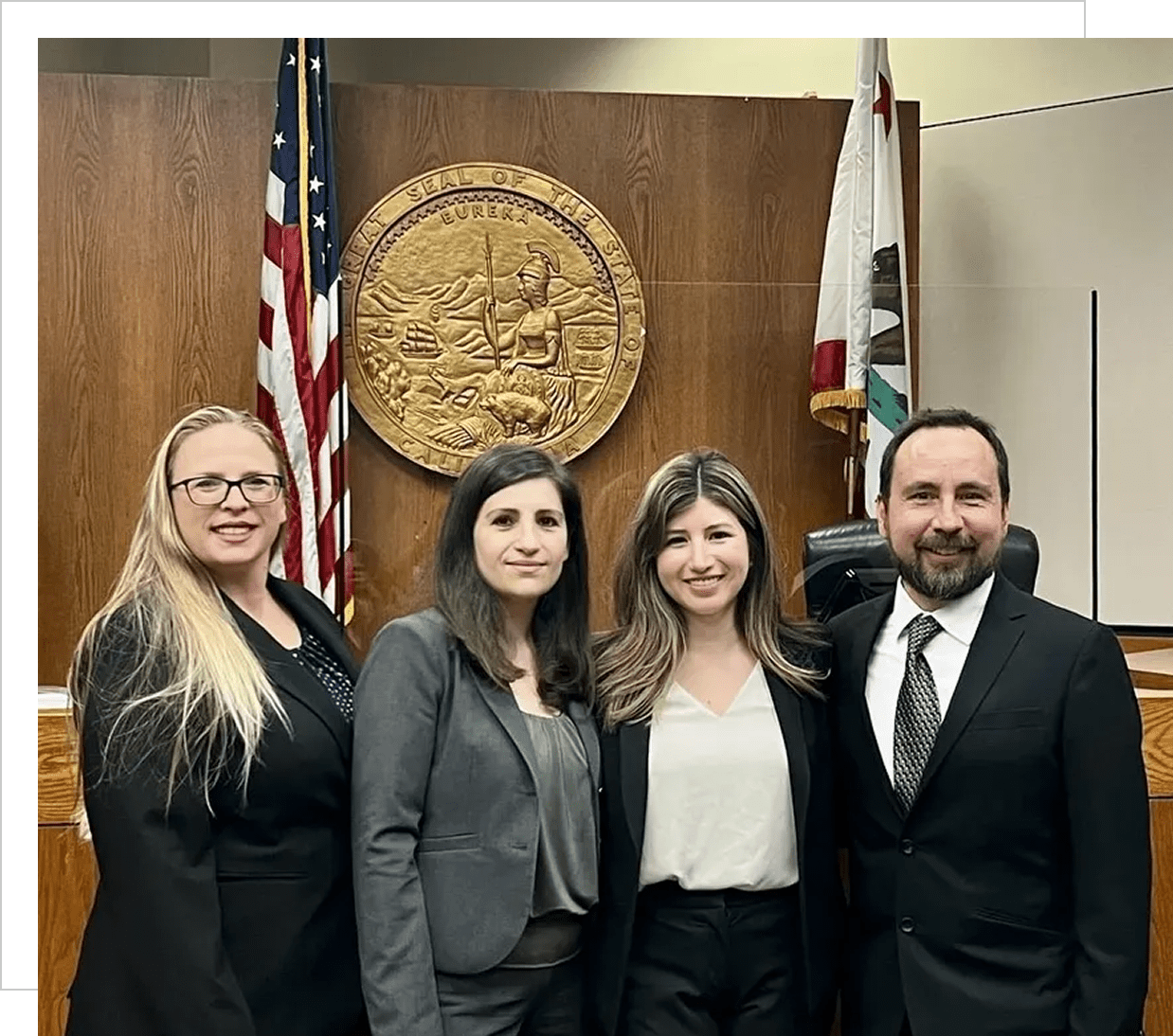 Four people in a courtroom setting, smiling.